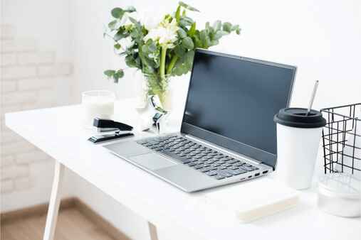 workplace, laptop and flowers on a white table top to demonstrate content optimisation